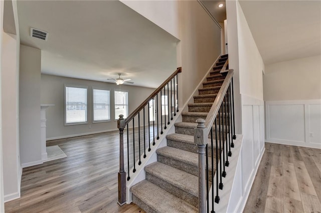 stairway with hardwood / wood-style floors and ceiling fan