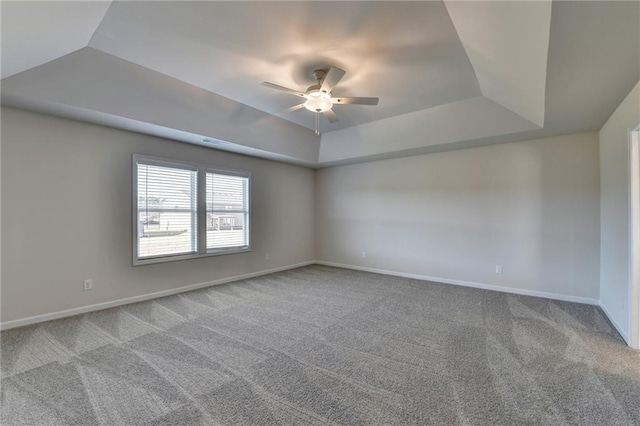 empty room featuring carpet, ceiling fan, and a raised ceiling