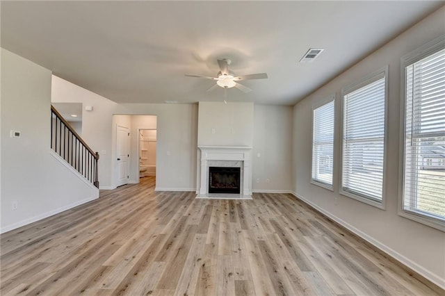 unfurnished living room featuring light wood-type flooring, ceiling fan, and a premium fireplace