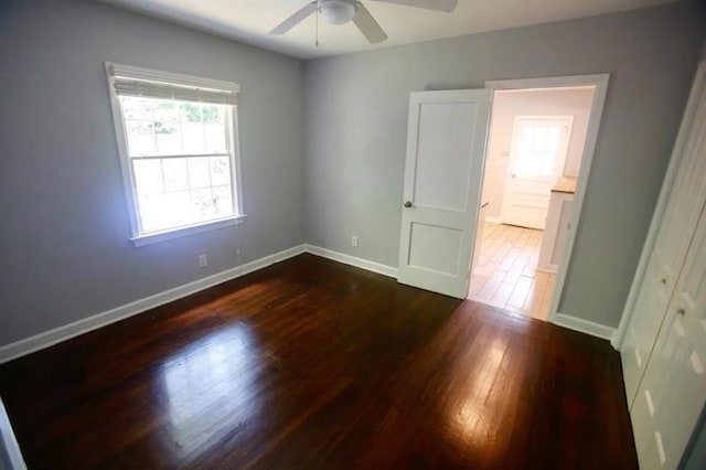 spare room featuring dark wood-style floors, a ceiling fan, and baseboards