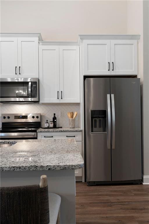 kitchen featuring appliances with stainless steel finishes, white cabinets, dark wood-type flooring, and decorative backsplash