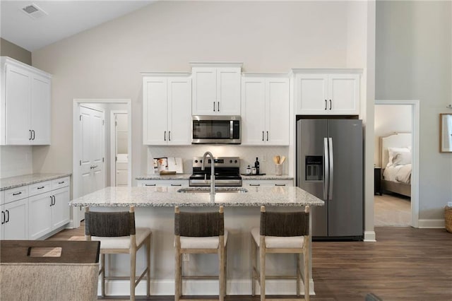 kitchen featuring stainless steel appliances, a sink, high vaulted ceiling, decorative backsplash, and white cabinetry
