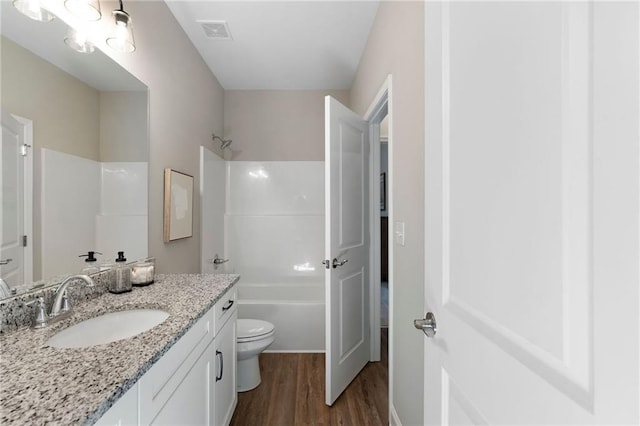bathroom featuring wood finished floors, vanity, shower / bath combination, and toilet