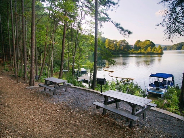 view of property's community featuring a water view, a wooded view, and a dock
