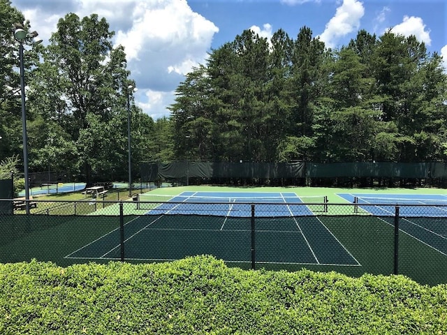 view of tennis court featuring community basketball court and fence