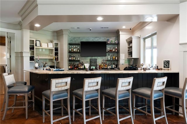indoor bar featuring ornamental molding, dark wood finished floors, and backsplash