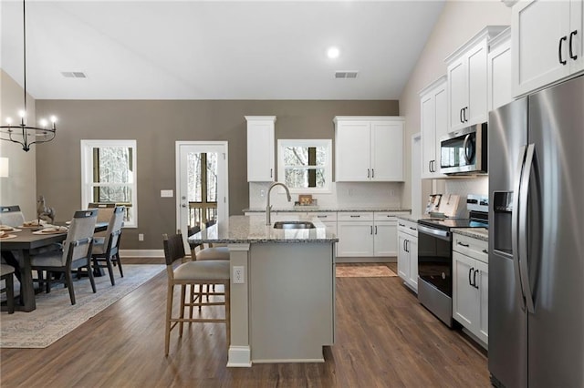 kitchen featuring appliances with stainless steel finishes, a sink, a chandelier, tasteful backsplash, and dark wood-type flooring