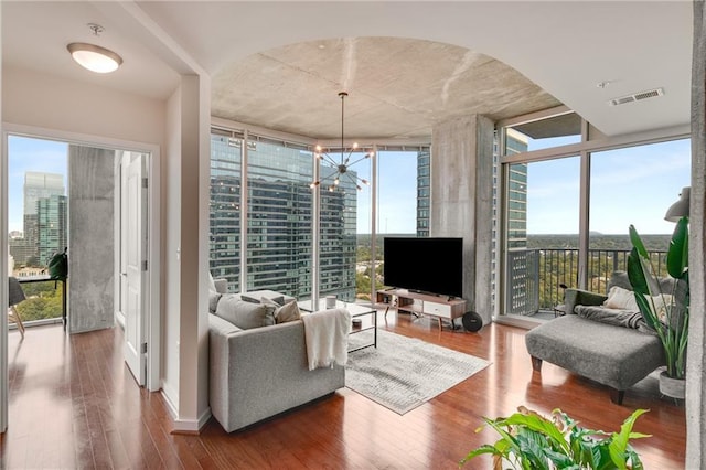 living area with a wall of windows, arched walkways, visible vents, and wood finished floors