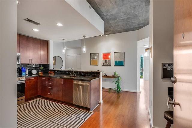 kitchen featuring tasteful backsplash, visible vents, appliances with stainless steel finishes, a sink, and a peninsula