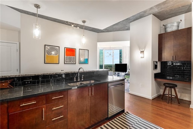 kitchen featuring dark wood-style flooring, a sink, backsplash, dishwasher, and decorative light fixtures