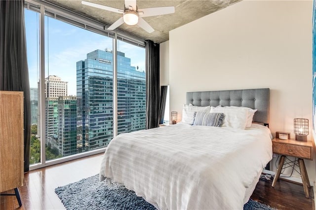 bedroom featuring a ceiling fan, floor to ceiling windows, a city view, and wood finished floors