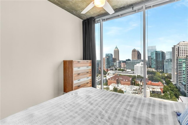 bedroom with a wall of windows, a ceiling fan, and a city view