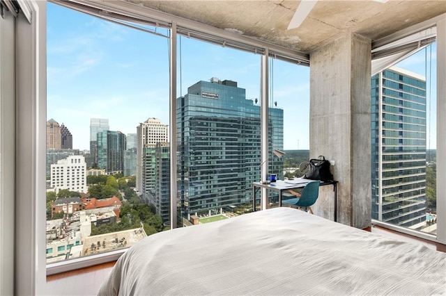 bedroom with a wall of windows, a view of city, and wood finished floors