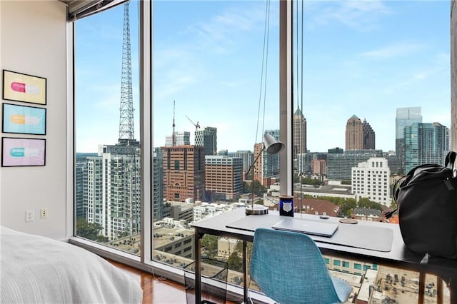 bedroom featuring a view of city, multiple windows, and wood finished floors