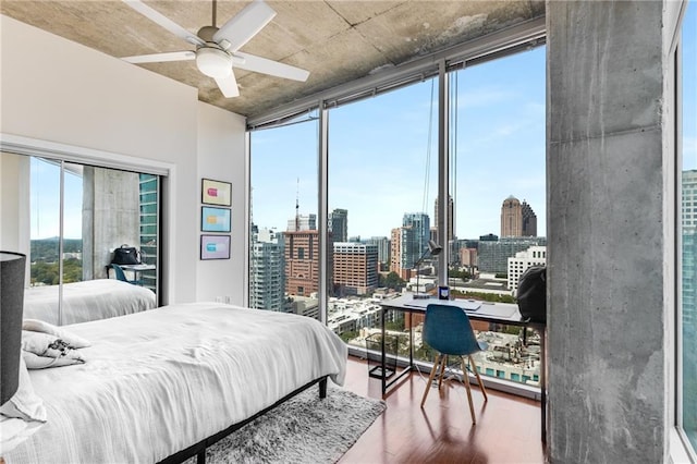 bedroom with a view of city, multiple windows, expansive windows, and wood finished floors