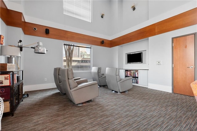 living room with a high ceiling, baseboards, and carpet flooring