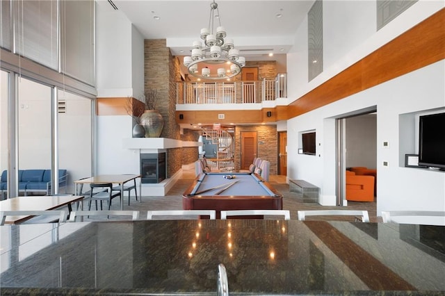 recreation room featuring a large fireplace, a notable chandelier, a high ceiling, and billiards