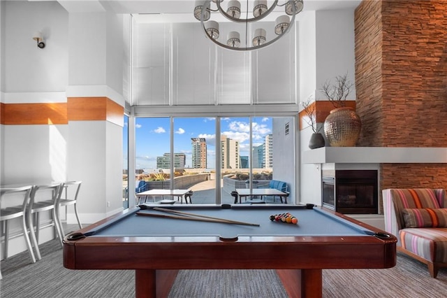 recreation room featuring a city view, a towering ceiling, a glass covered fireplace, carpet flooring, and billiards