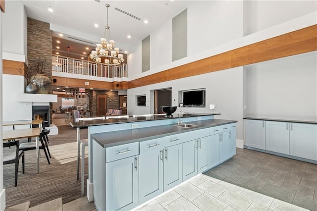 kitchen with dark countertops, open floor plan, a sink, and a glass covered fireplace