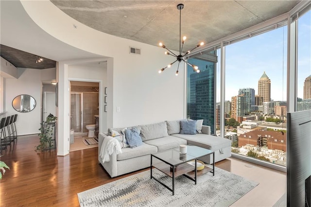 living area with expansive windows, a healthy amount of sunlight, visible vents, and wood finished floors