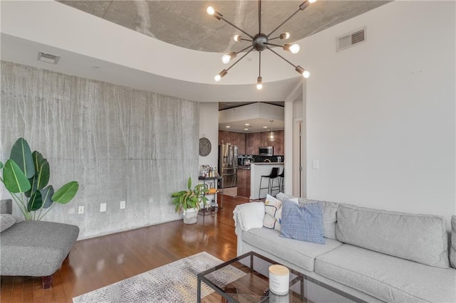 living room with an inviting chandelier, visible vents, and wood finished floors