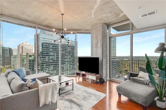 living room featuring a healthy amount of sunlight, wood finished floors, visible vents, and floor to ceiling windows