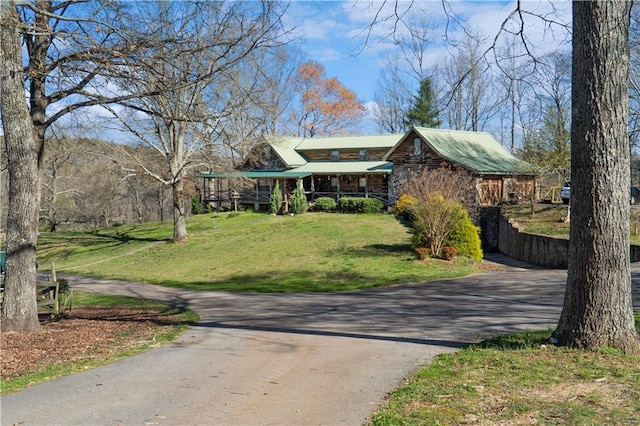 view of front facade with metal roof, driveway, and a front lawn
