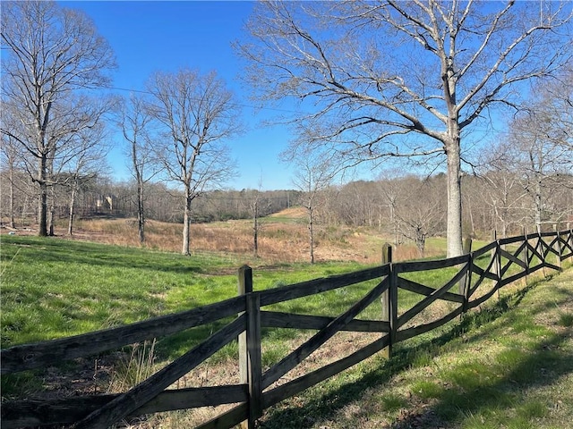 view of gate featuring a lawn, fence, and a rural view