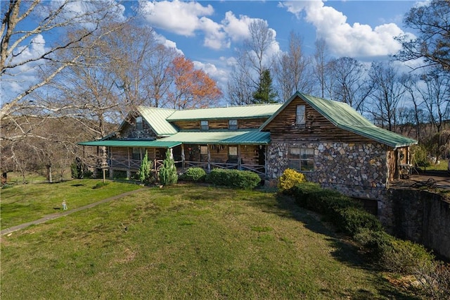 back of house with covered porch, stone siding, log exterior, metal roof, and a lawn