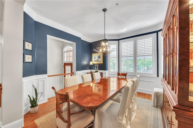 dining space featuring a notable chandelier, ornamental molding, and light hardwood / wood-style flooring