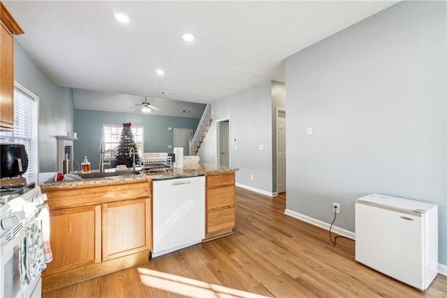 kitchen featuring light stone countertops, white appliances, ceiling fan, sink, and light hardwood / wood-style flooring