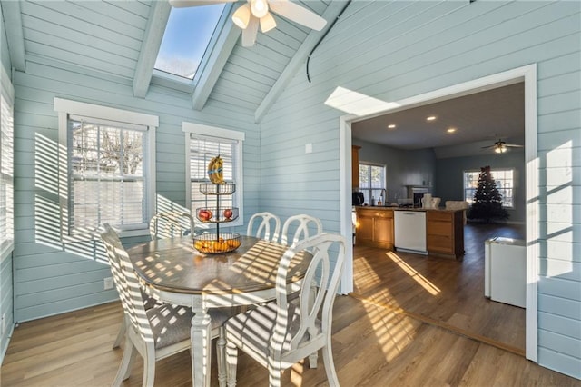 dining space featuring lofted ceiling with skylight, plenty of natural light, ceiling fan, and light hardwood / wood-style floors