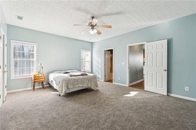 bedroom featuring ceiling fan, dark carpet, a textured ceiling, and multiple windows