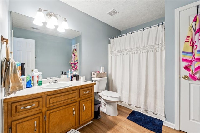 full bathroom featuring vanity, wood-type flooring, a textured ceiling, and toilet