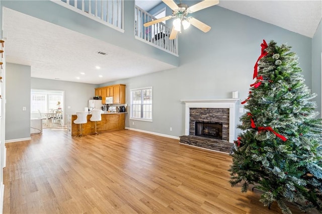 unfurnished living room with a fireplace, light hardwood / wood-style floors, ceiling fan, and a healthy amount of sunlight