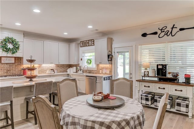 kitchen with sink, backsplash, white cabinets, light hardwood / wood-style floors, and stainless steel appliances