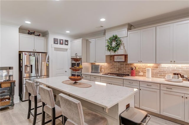 kitchen featuring a kitchen island, light stone countertops, appliances with stainless steel finishes, and white cabinets