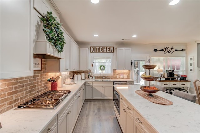 kitchen featuring stainless steel gas stovetop, light stone countertops, sink, and white cabinets