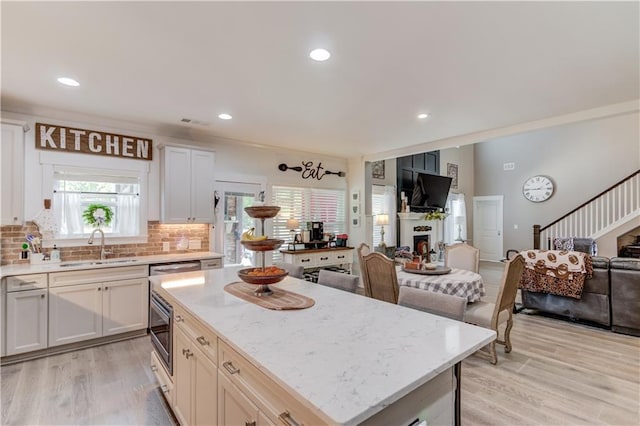 kitchen featuring a center island, sink, light hardwood / wood-style flooring, and white cabinets