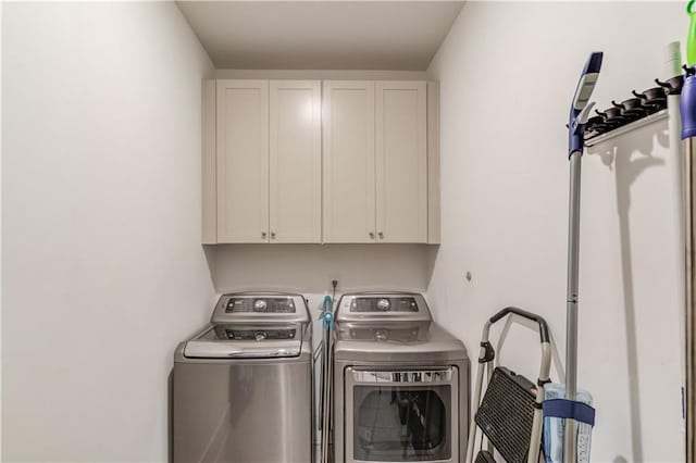 clothes washing area with independent washer and dryer and cabinets