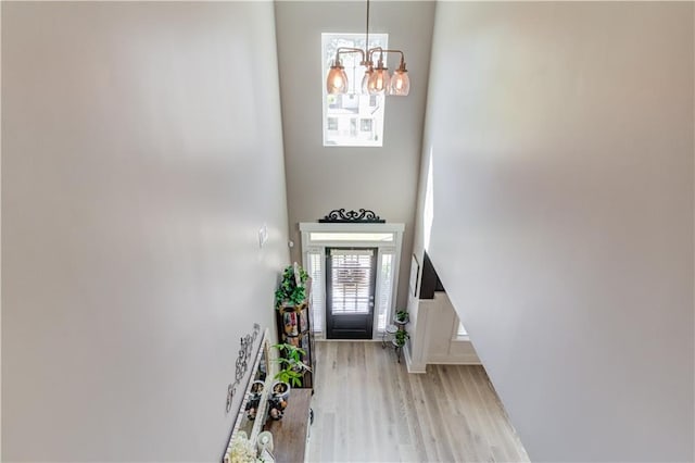 entrance foyer with a notable chandelier, light hardwood / wood-style flooring, and a high ceiling