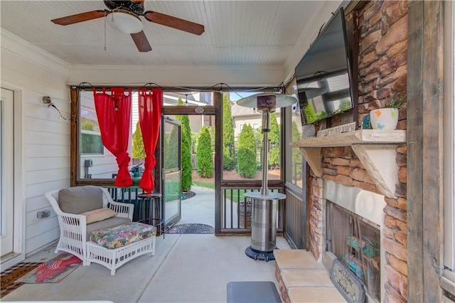 sunroom featuring ceiling fan and an outdoor stone fireplace