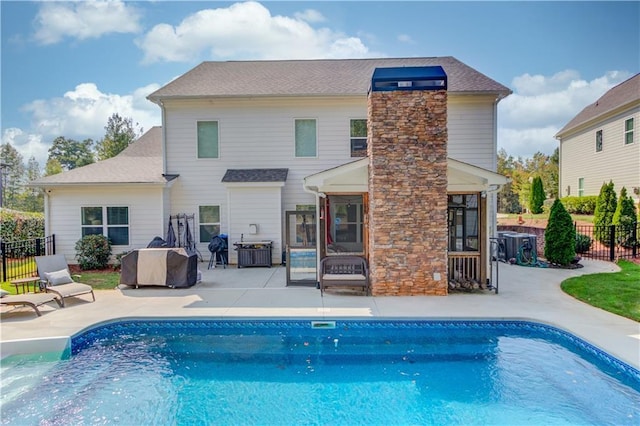 rear view of house featuring a sunroom, a fenced in pool, and a patio area