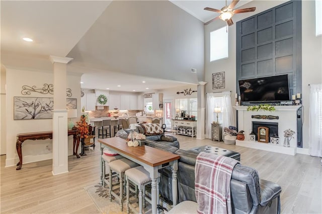 living room featuring ornate columns, ceiling fan, high vaulted ceiling, and light hardwood / wood-style floors