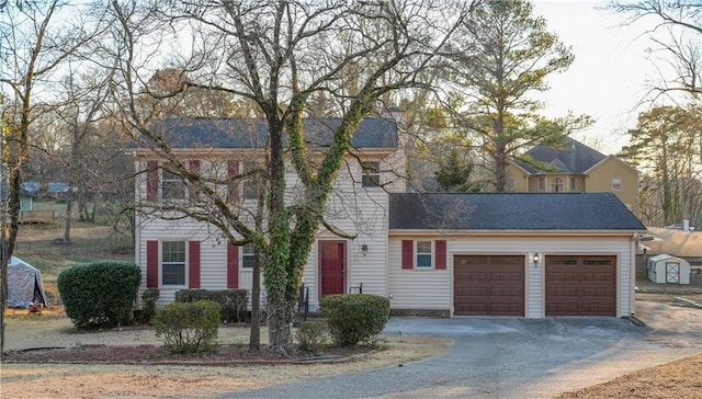 colonial home featuring a garage, roof with shingles, and driveway