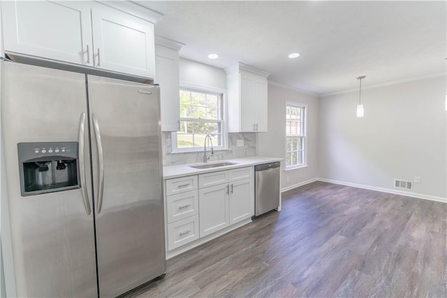 kitchen with stainless steel appliances, a sink, wood finished floors, light countertops, and white cabinetry
