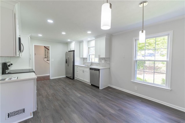 kitchen featuring stainless steel appliances, a sink, ornamental molding, dark wood finished floors, and baseboards
