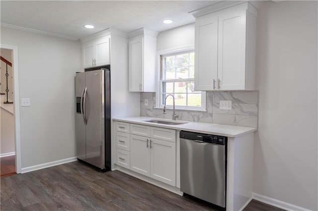 kitchen with appliances with stainless steel finishes, a sink, dark wood-style floors, decorative backsplash, and white cabinetry