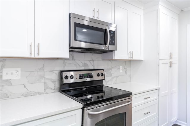 kitchen featuring stainless steel appliances, light countertops, white cabinets, and decorative backsplash