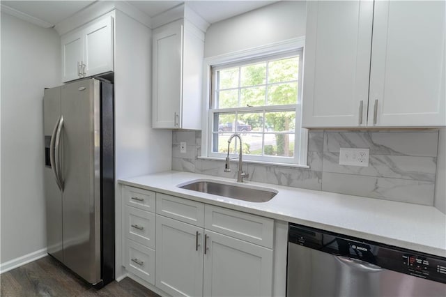 kitchen featuring appliances with stainless steel finishes, a sink, decorative backsplash, and white cabinetry